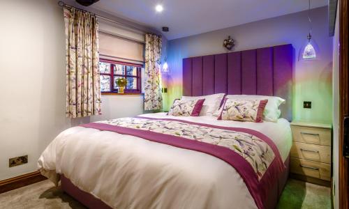 CrosthwaiteにあるTipsy Gin Cottageのベッドルーム(紫色のヘッドボード付きの大型ベッド1台付)
