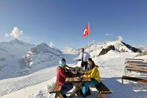 a group of people sitting at a table on top of a mountain at Carpe Diem 2 in Fiesch