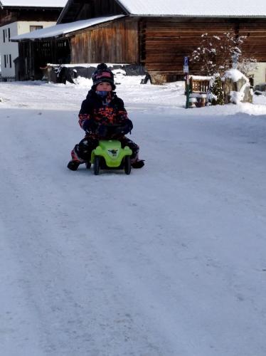 a child riding a toy car in the snow at M4 Appartements in Wagrain