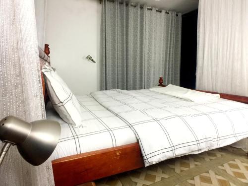 ein Schlafzimmer mit einem Bett mit weißer Bettwäsche und einer Lampe in der Unterkunft Studio Ghibli 1BR1B in Kampala
