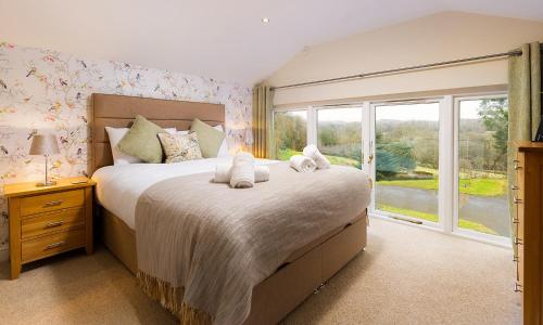 een slaapkamer met een groot bed en een groot raam bij Cragfell Cottage in Cartmel