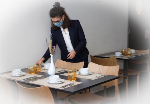 a woman wearing a face mask standing at a table at Bourquin Hotel - Lycée Hôtelier Christian Bourquin in Argelès-sur-Mer