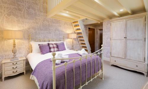 ein Schlafzimmer mit einem Bett mit violetter Bettwäsche und einer Leiter in der Unterkunft Crow Cottage in Keswick