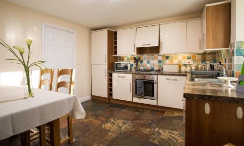 a kitchen with white cabinets and a table with a vase at Woodside West in Bowness-on-Windermere