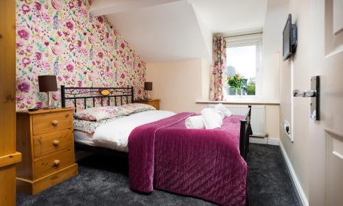 a bedroom with a bed with a purple blanket at Woodside West in Bowness-on-Windermere