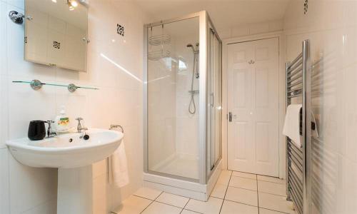 a white bathroom with a sink and a shower at Woodside West in Bowness-on-Windermere