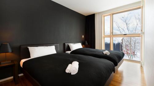 two beds in a room with black walls and a window at Forest Estate in Kutchan