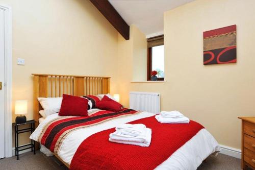 a bedroom with a red and white bed with towels on it at A River Runs By in Staveley