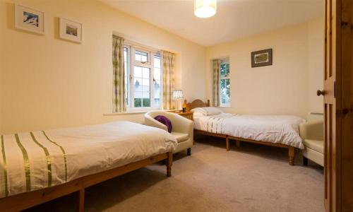 a bedroom with two beds and a chair and a window at Grange Fell Borrowdale in Keswick