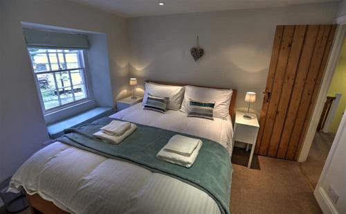 a bedroom with a large bed with towels on it at Townfoot Cottage in Elterwater