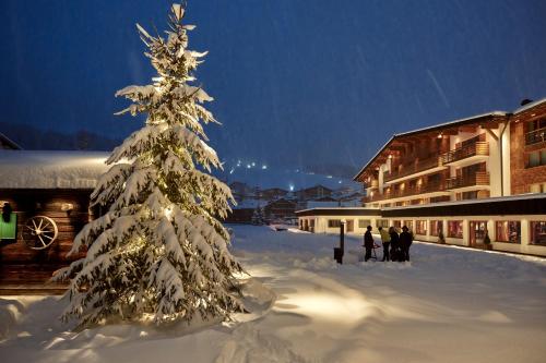 a christmas tree covered in snow in front of a building at Hotel Auriga in Lech am Arlberg