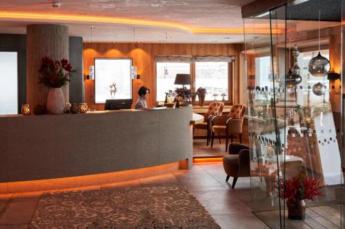 a woman sitting at a counter in a restaurant at Hotel Auriga in Lech am Arlberg