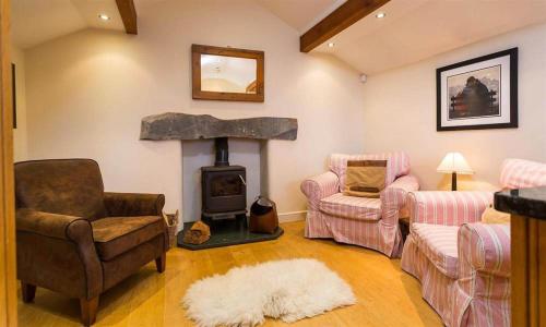 a living room with a fireplace and a couch and chairs at Ivy Cottage in Ambleside