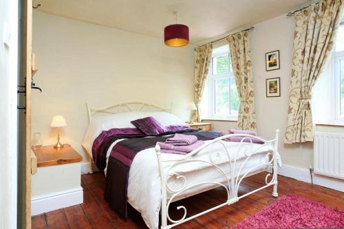 a bedroom with a white bed and a pink rug at Stone Cottage at Staveley in Windermere