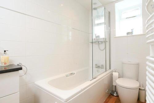 a white bathroom with a tub and a toilet at Stone Cottage at Staveley in Windermere