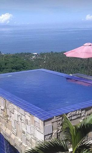 a swimming pool with an umbrella and the ocean at Rara Villas Lombok in Senggigi 