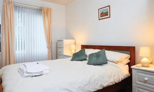 ボウネス・オン・ウィンダミアにあるMossleaのベッドルーム1室(白いシーツと緑の枕が備わるベッド1台付)