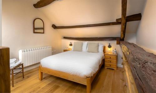 a bedroom with a large white bed and wooden floors at Barn Cottage in Cockermouth