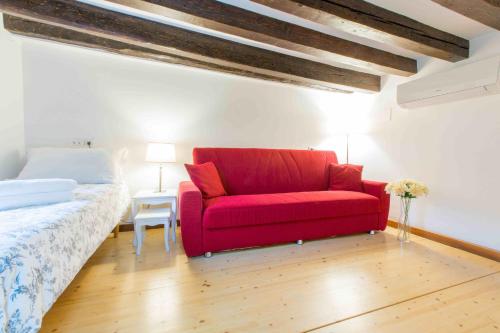 um sofá vermelho num quarto com uma cama em CA CICOGNA air conditioning and fast WiFi, central location apartment em Veneza
