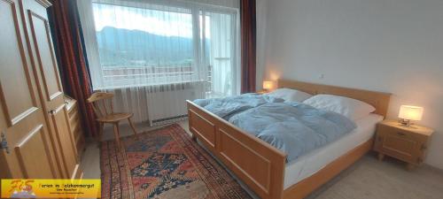 a bedroom with a bed with a blue comforter and a window at Apartment Alpenpanorama by FiS - Fun in Styria in Bad Mitterndorf