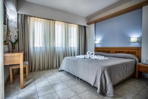 a bedroom with a bed and a desk and a window at Mary Hotel & Mary Royal Suites in Platanes