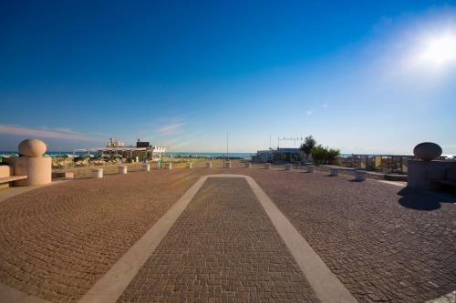 a walkway with benches and the ocean in the background at Hotel Baltic in Misano Adriatico