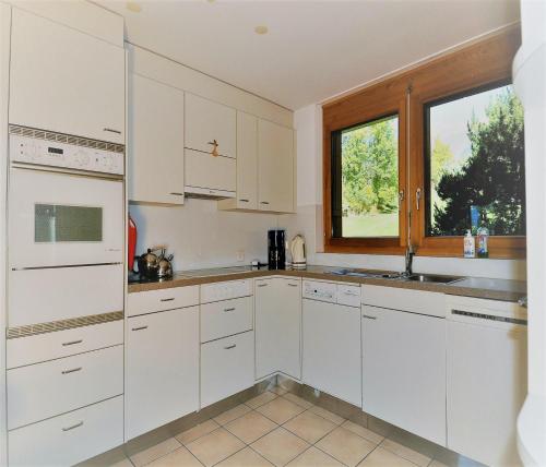 a white kitchen with white cabinets and a window at Aleid Sunshine in Fiesch