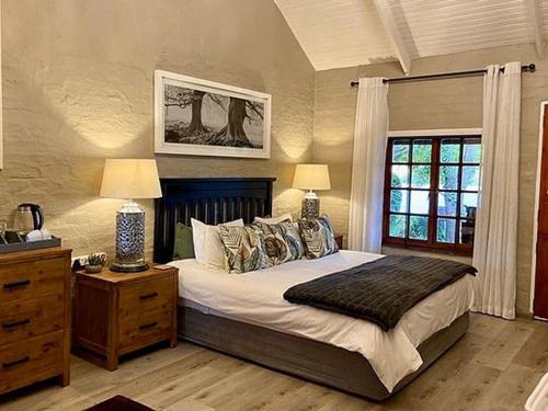 a bedroom with a bed with two lamps and a window at Lakeside Chalets Critchley Hackle Lodge in Dullstroom