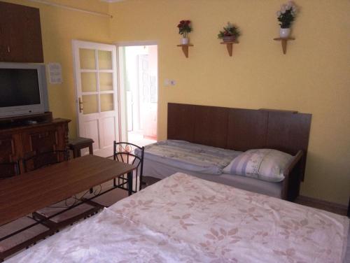 a bedroom with two beds and a tv and a table at Szivárvány Apartman in Gyula