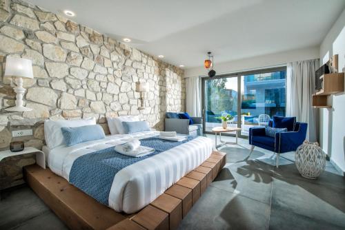 1 dormitorio con 1 cama grande y pared de piedra en Mary Hotel & Mary Royal Suites en Platanés