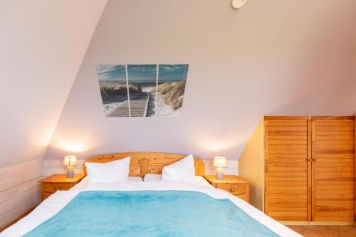 a bedroom with a bed with a blue comforter at Maashof Nis Puck in Husum