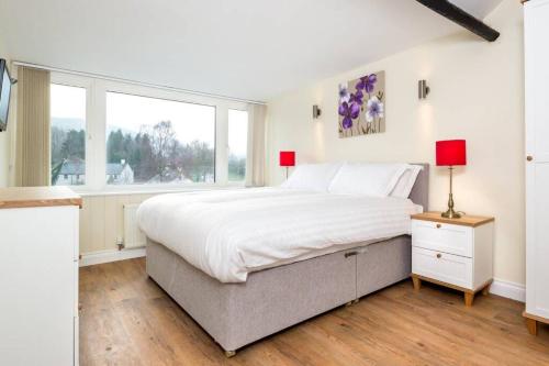 a white bedroom with a large bed and a window at Lake Road Apartment Keswick in Keswick