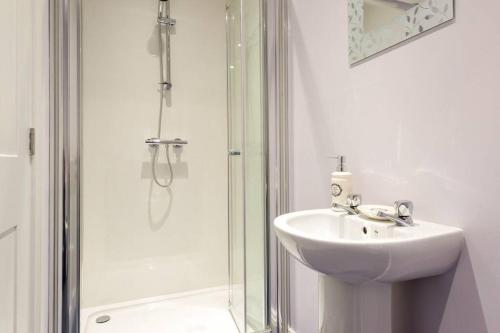 a white bathroom with a sink and a shower at Lake Road Apartment Keswick in Keswick