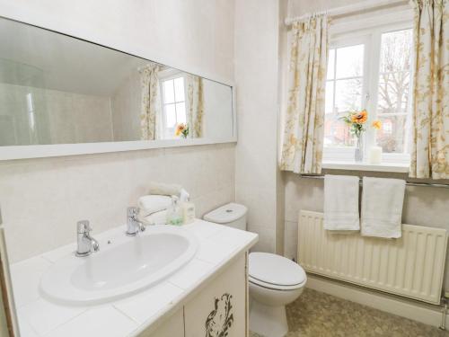 a bathroom with a sink and a toilet and a mirror at Heath Cottage in Stratford-upon-Avon