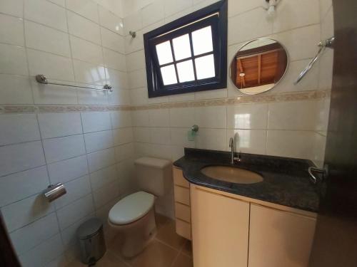 a bathroom with a sink and a toilet and a window at Casa Village Ilha de Mykonos in Juquei