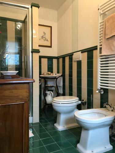a green and white bathroom with a toilet and a sink at Agriturismo Collerisana in Spoleto