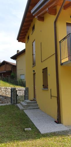 a yellow house with stairs and a balcony on it at Casa Ramus Valle Camonica a 30 km dal Passo Tonale in Edolo