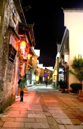 a woman walking down a street at night at Mild Spring Boutique Hotel in Huangshan