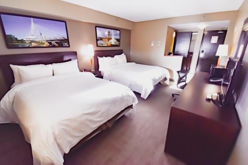 a hotel room with two beds and two monitors at Canad Inns Destination Centre Polo Park in Winnipeg