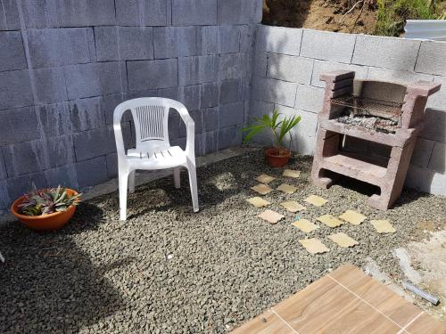 a white chair sitting in a yard next to a wall at Bungalow Alizé in Le Robert
