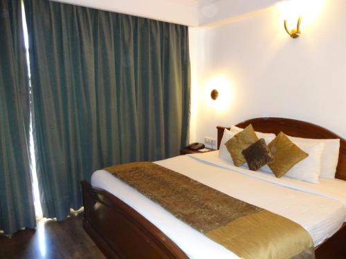 a bedroom with a large bed with green curtains at Hotel Combermere in Shimla
