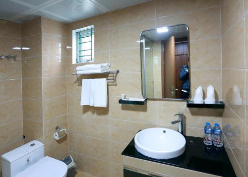 y baño con aseo, lavabo y espejo. en Olala Hotel en Cẩm Phả