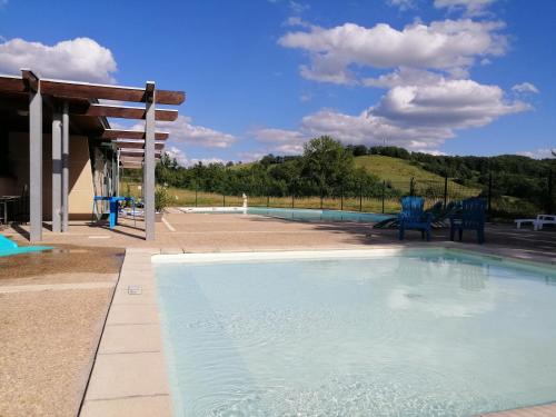 uma piscina com duas cadeiras azuis ao lado em Village Bord de Ciel em Caylus
