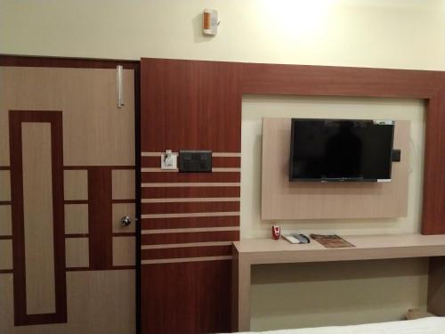 Habitación de hotel con TV y dormitorio con cama en Hotel delight deluxe, en Pipra Dewās