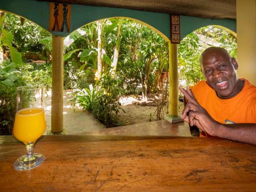 a man sitting at a table with a glass of orange juice at Auberge Africa Thiossane in Saly Portudal