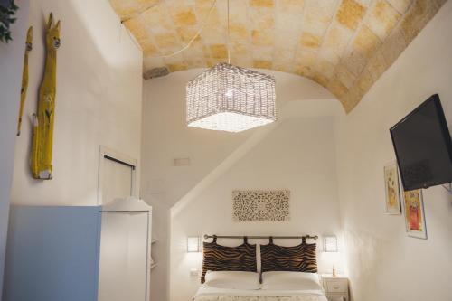 una camera con un letto e un soffitto con un lampadario a braccio di HolidayMonopoli a Monopoli