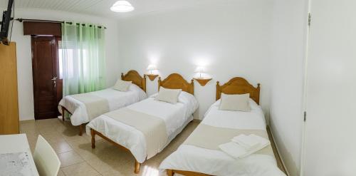 a room with three beds and a mirror at Hospedaria Australia in Velas
