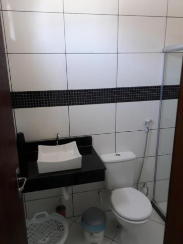 a small bathroom with a toilet and a sink at Casa de Temporada Guaibim in Guaibim
