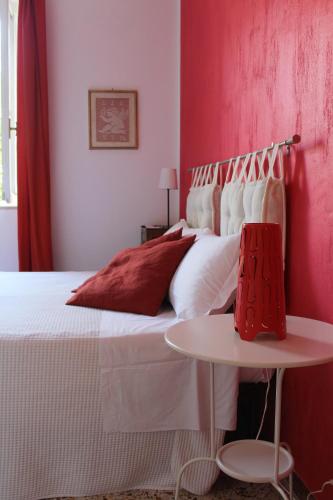 a bedroom with a bed with red walls and a table at Alle Terme B&B in Rapolano Terme