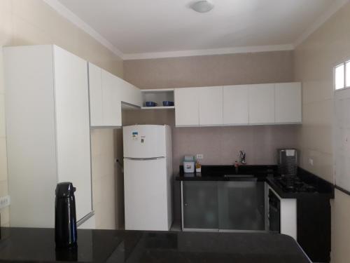 a kitchen with white cabinets and a white refrigerator at Casa de Temporada Guaibim in Guaibim